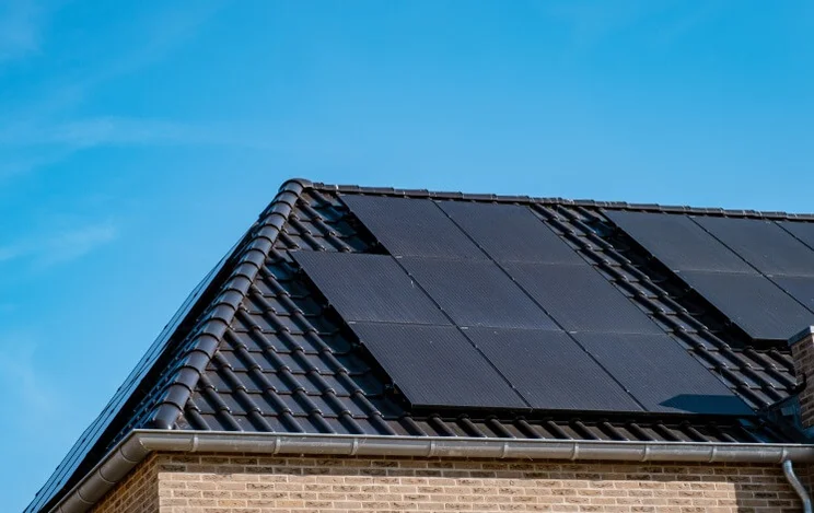 black-solar-panels-on-a-dark-roof-under-a-blue-sky